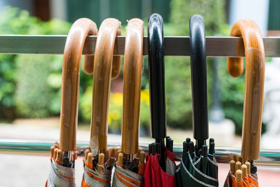 Closed-folding-umbrellas-with-handles-hanging-on-a-rail-